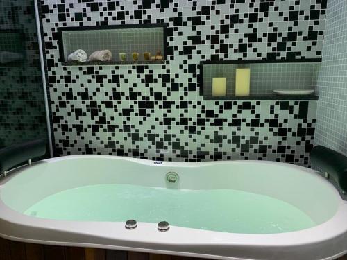 a bath tub in a bathroom with black and white tiles at Maravilhoso apartamento 2 quartos com ofurô Porto da Barra Salvador Summer Barra Flat in Salvador