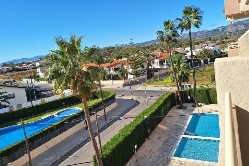 uitzicht op een zwembad met palmbomen en huizen bij Apartamento muy cerca del mar, piscina, a/a, wifi y garaje. in Benicàssim