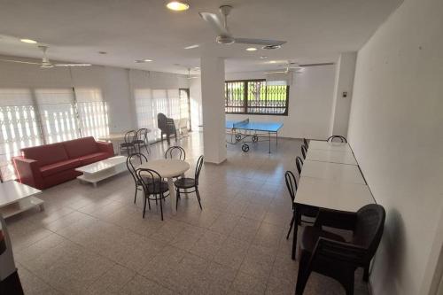 een woonkamer met een bank en tafels en stoelen bij Apartamento muy cerca del mar, piscina, a/a, wifi y garaje. in Benicàssim