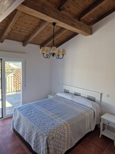 a bedroom with a bed and a chandelier at Casa Las Tejeras in Casavieja