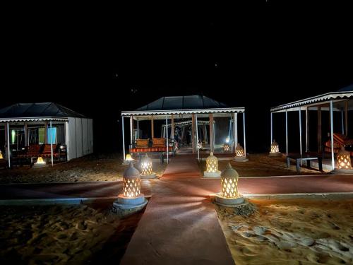 un pabellón de noche con luces en la arena en Merzouga Dunes Luxury Camps, en Merzouga