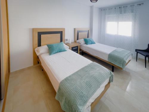 1 dormitorio con 2 camas, silla y ventana en Sunny Three bedroom apartment, en San Pedro del Pinatar