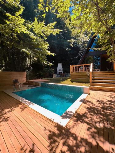 a swimming pool with a wooden deck next to a house at Chalet Sapanca in Sakarya
