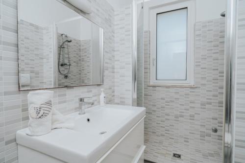 a white bathroom with a sink and a mirror at Villa Posidonia in San Lorenzo