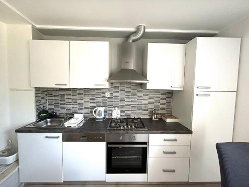 a kitchen with white cabinets and a stove top oven at TENA in Kukuljanovo