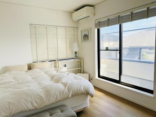 a bedroom with a bed and a large window at Accessible Four-Bedroom House near Kuzuha Station! in Hirakata