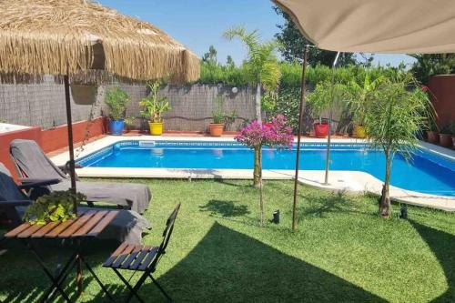 een achtertuin met een zwembad met een parasol bij Casa Bignonia in Salteras