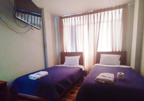 two beds in a small room with a window at Hallpa Ica in Ica