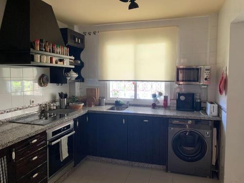 een keuken met blauwe kasten en een wasmachine bij Casa Bignonia in Salteras