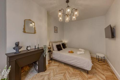 1 dormitorio con cama, chimenea y lámpara de araña en Appart luxueux hyper-centre/15mn Fontainebleau, en Montereau-Fault-Yonne