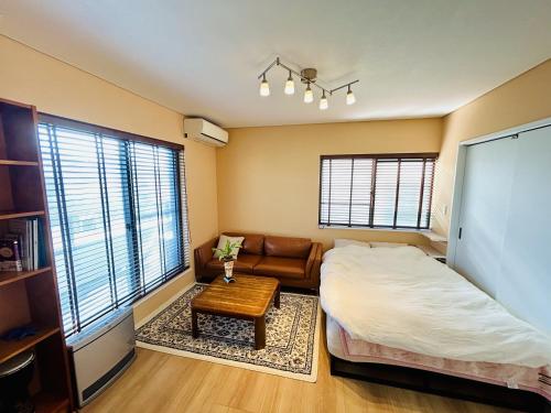 a bedroom with a bed and a couch and a table at Accessible Four-Bedroom House near Kuzuha Station! in Hirakata
