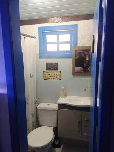 a bathroom with a toilet and a sink and a window at Sítio Canto da Roça Com Cachoeira in Domingos Martins