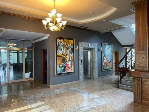 a lobby with a chandelier and paintings on the walls at Misk Hotel & Resort in Tirana