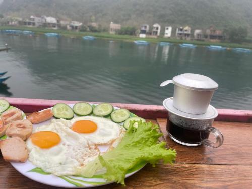 a plate of eggs and vegetables and a cup of coffee at Cornflower Homestay PHONG NHA in Phong Nha