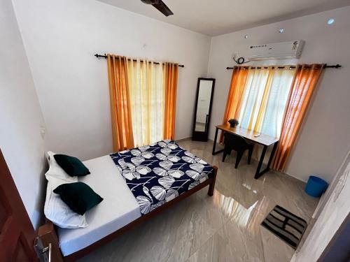 a bedroom with a bed and a desk and curtains at Paddy N Canal Homestay in Alleppey