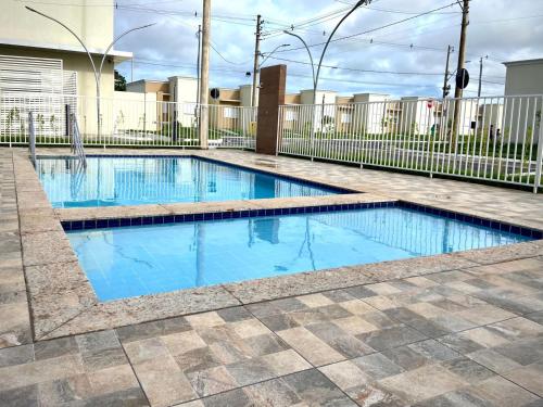 - une piscine d'eau bleue dans la cour dans l'établissement Casa em condomínio fechado, à Cuiabá