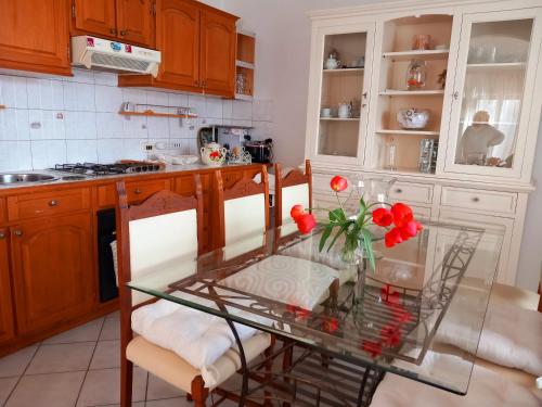 a kitchen with a glass table with red flowers on it at La Maison des Rèves -Langhe Piemonte in Torre Bormida