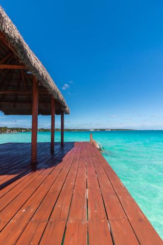 a wooden dock with a thatched roof on the water at Mayan Playa Bacalar in Bacalar