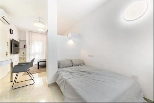 a white bedroom with a bed and a chair at Sababa Host-Boutique Rooms in Central Tel Aviv in Tel Aviv