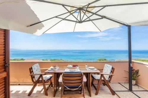 a table and chairs on a balcony with an umbrella at Amazing BAY VIEW-BEACH BOUTIQUE Apartment VELAMEIGA in Funtana Meiga
