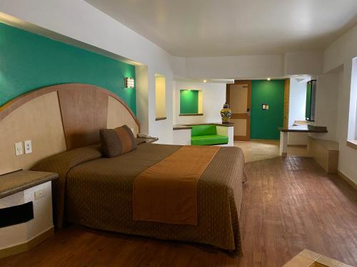 Habitación de hotel con cama y pared verde en Hotel Villa de Madrid, en Ciudad de México