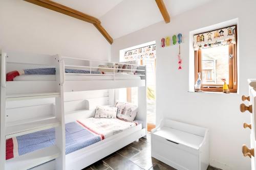 a bedroom with two bunk beds and a mirror at Re-imagined Stone Barns in the Country Near the Coast in Padstow
