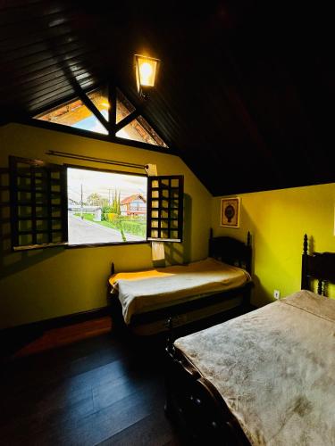 two beds in a room with a window at Chalé Charmoso em Bananeiras no condomínio exclusivo Serra Nevada in Bananeiras