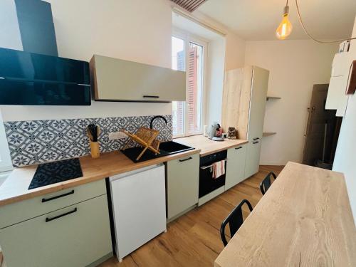 una cocina con armarios blancos y una mesa. en L’appartement lumière, en Bourg-en-Bresse