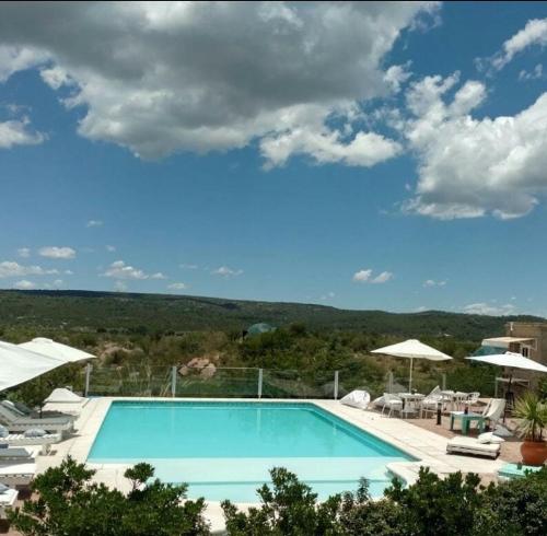 a large swimming pool with chairs and umbrellas at DOS AGUAS in Capilla del Monte
