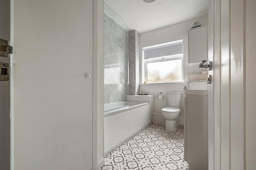 a bathroom with a toilet and a tub and a sink at Pass the Keys Bright holiday apartment near the beach in Dawlish