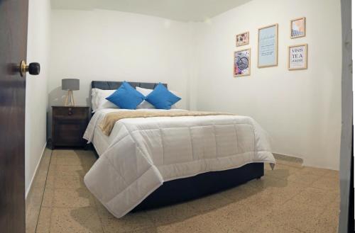 a bedroom with a large bed with blue pillows at Familiar y acogedor in Medellín