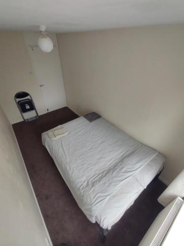 um pequeno quarto com uma cama branca em Homestay near a station and park em Longbridge