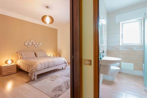 a bedroom with a bed and a bathroom with a sink at Montellinos Suite Tortora in SantʼAntìoco