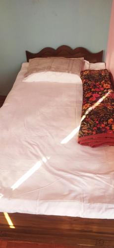 ein Bett mit weißer Bettwäsche und einem Schal darauf in der Unterkunft Kantipur community homestay in Chitwan