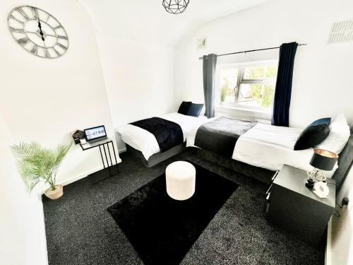 a bedroom with two beds and a clock on the wall at Watford Central Luxury Serviced Accommodation in Watford