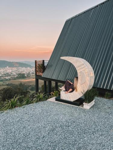 a woman is sitting in a chair under a umbrella at Cabana Lua Crescente Ituporanga in Ituporanga
