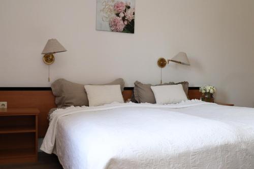 a bedroom with a large white bed with two lamps at Landhaus Ellernkrug Hotel in Lage