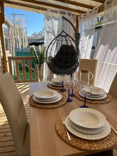 une table en bois avec des assiettes, des verres et une chaise dans l'établissement Bungalow Vias Plage, à Vias
