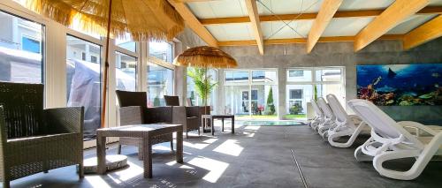 a restaurant with white chairs and a swimming pool at Srebrna Wydma Resort in Dąbki