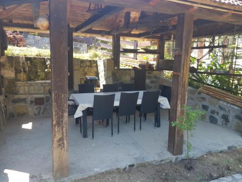 a table and chairs under a wooden structure at Kojadinovica Koliba in Mokra Gora