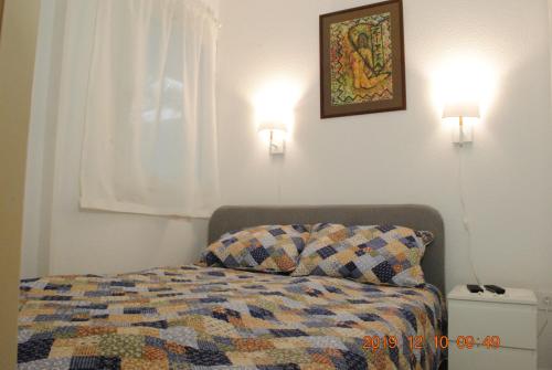 een slaapkamer met een bed met een quilt en 2 verlichting bij ideal appartement au calme prés du Golf in La Grande-Motte