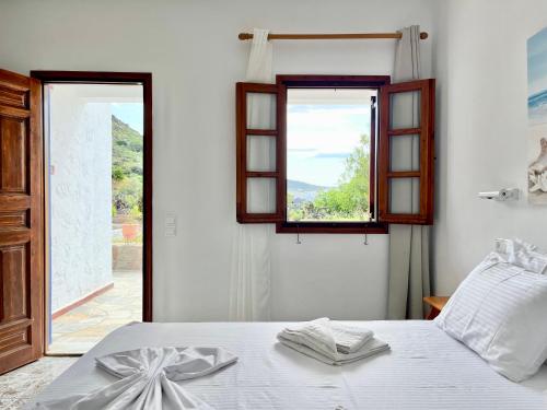 a white bedroom with a bed with a window at Nicolas Studios in Skala