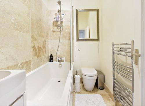 a bathroom with a tub and a toilet and a sink at Charming Apartment in Chelsea in London