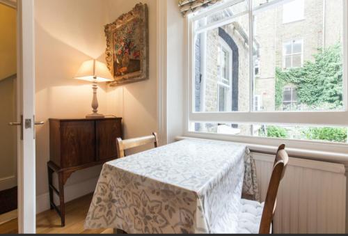 a dining room with a table and a window at Charming Apartment in Chelsea in London