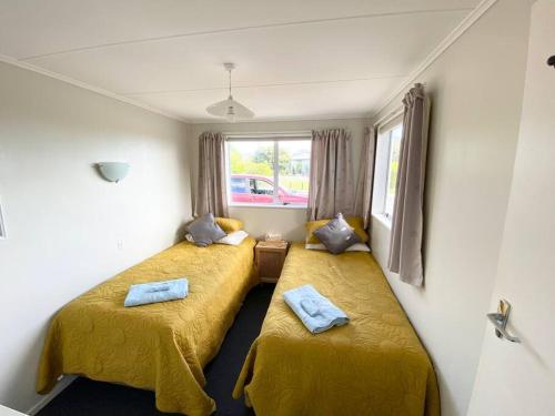 Pohara的住宿－Pohara's Seaside Chalet，配有黄色床单的客房内的两张床