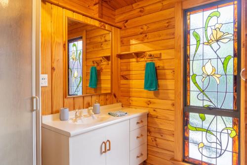 uma casa de banho com um lavatório e um vitral. em The Birds Nest - Nestled Hideaway em Takaka
