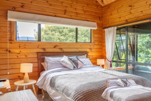 ein Schlafzimmer mit einem Bett und zwei Fenstern in der Unterkunft The Birds Nest - Nestled Hideaway in Takaka