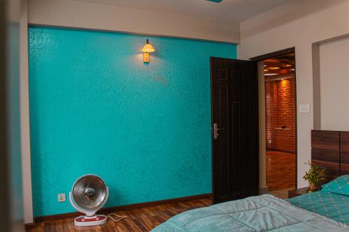 a bedroom with a blue wall and a fan at Suku family house. in Pātan