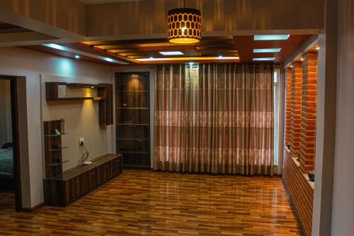 Suku family house. في باتان: غرفة معيشة مع ستارة كبيرة وغرفة مع أرضيات خشبية