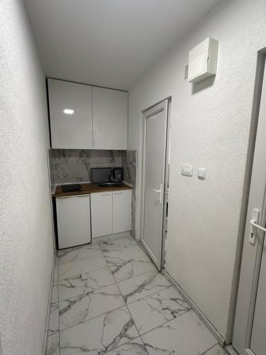 gvero apartment’s في بريليب: مطبخ وأرضيات رخام وجدران بيضاء